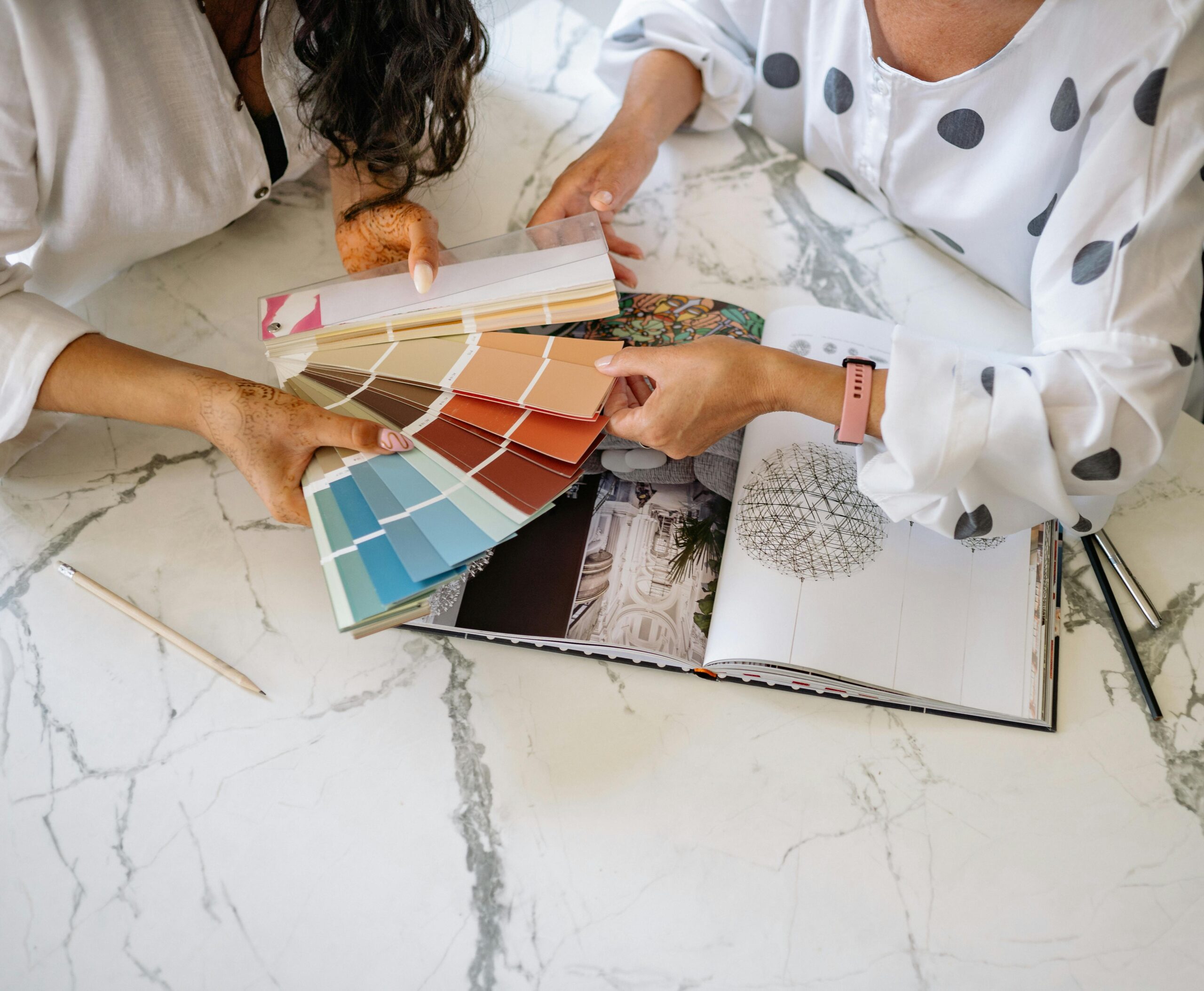 Two women in an office collaborating on color palettes for interior design planning.